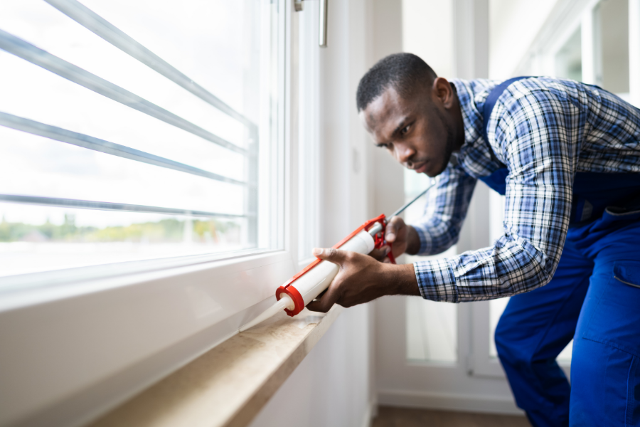 Man insulating windows and doors in home.