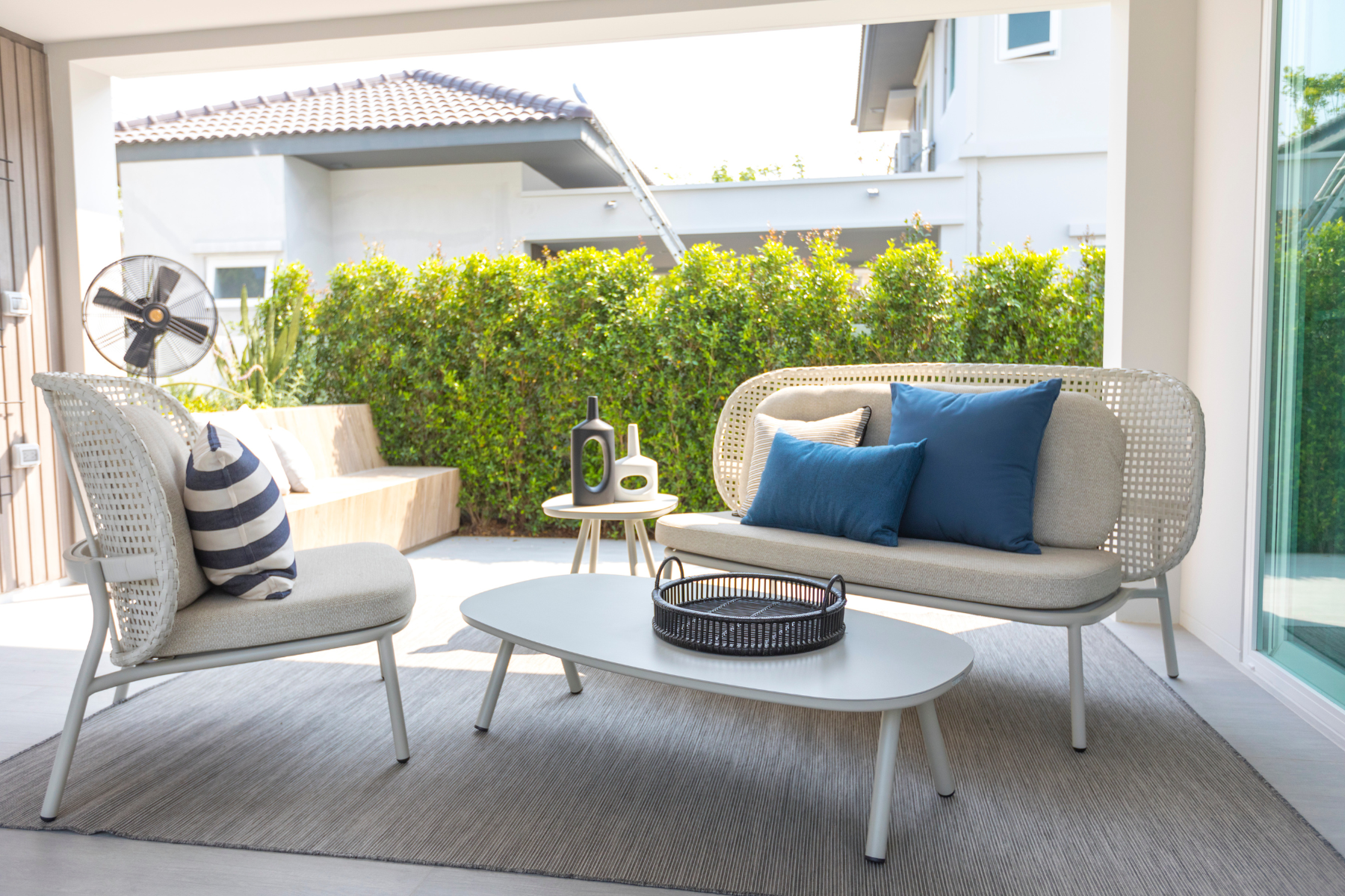 A modern minimalist patio set with aluminum furnishings with neutral and blue tones for the cushions