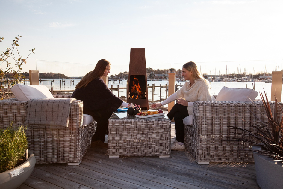 Sisters sit across from each other on a backyard patio overlooking the water