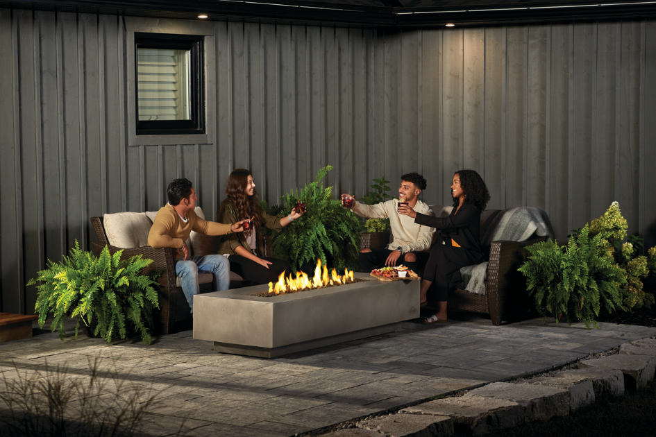 A group of friends sit around a fire table toasting to their evening.