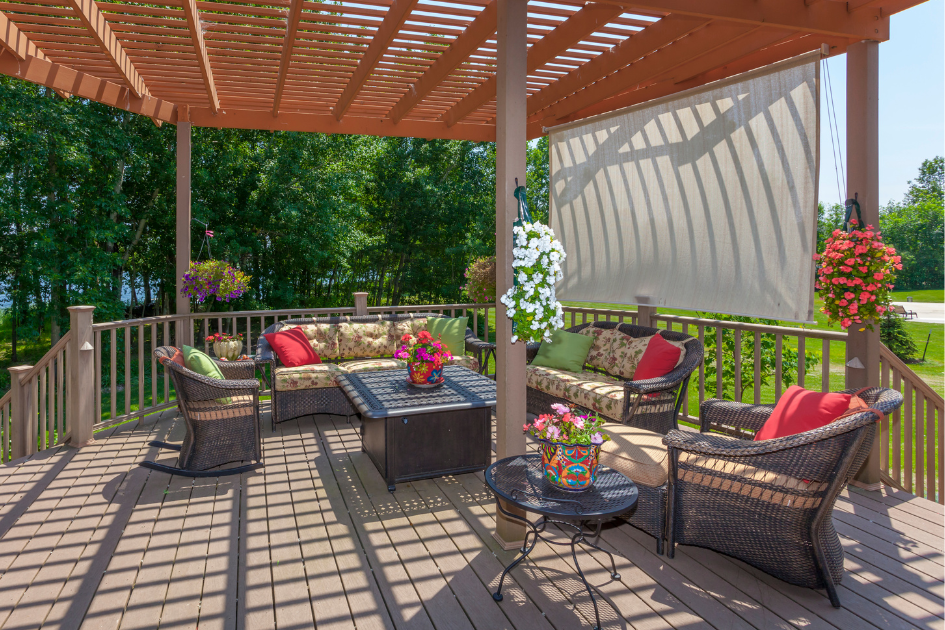 A covered backyard deck with bright flowers all around