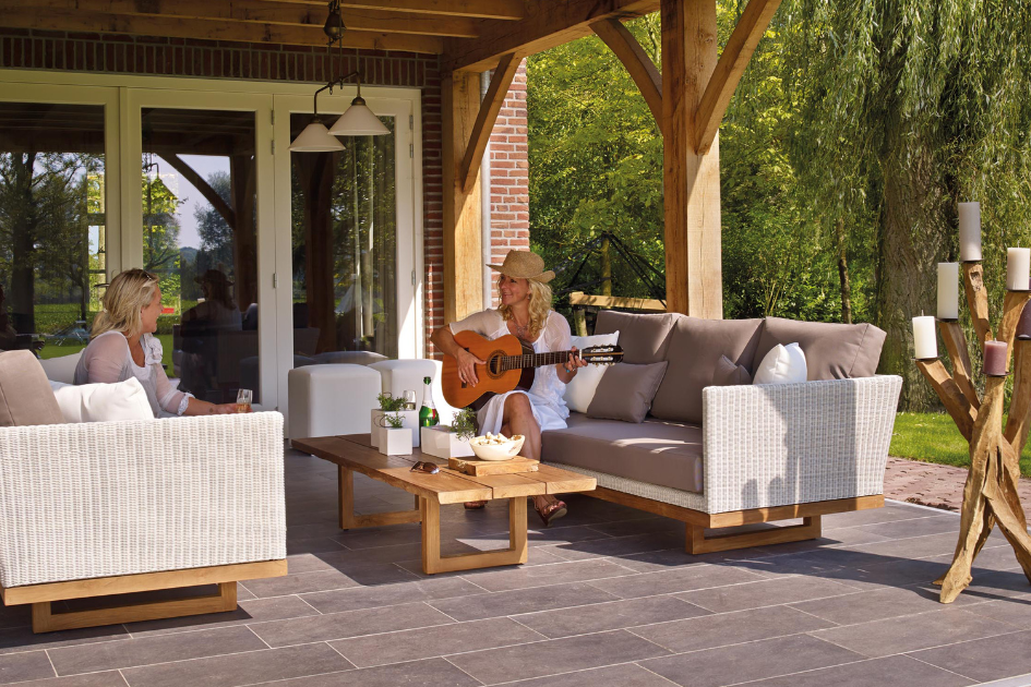 Sisters sit across from each other on their patio, one with a guitar plays. 