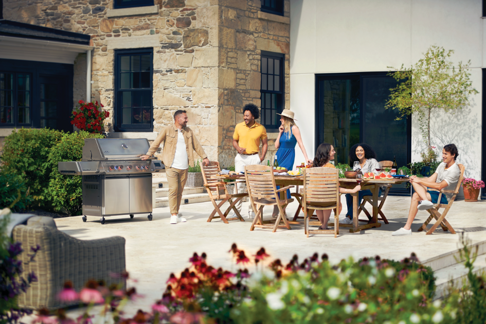 a group of friends gather around a patio setup for a BBQ